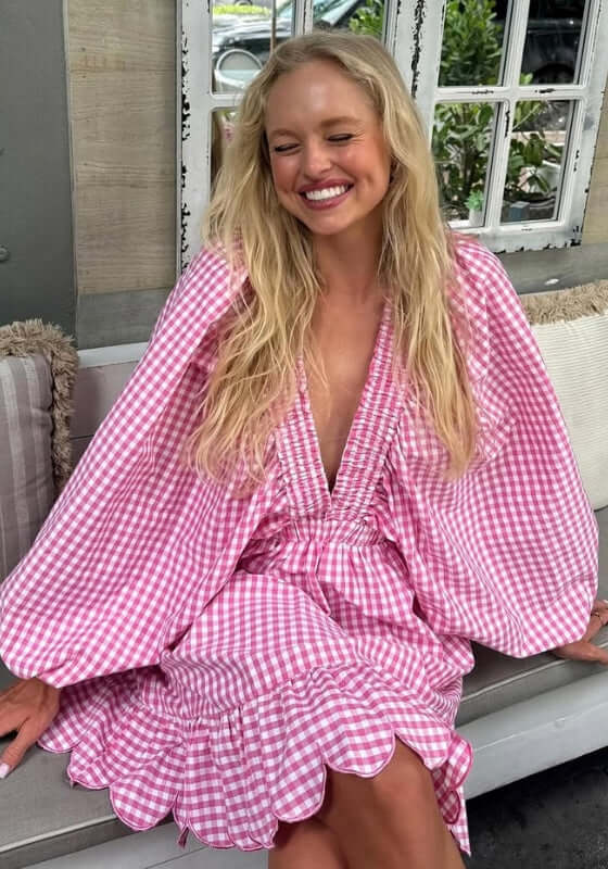 Marine Short Dress by Sundress, a model in pink gingham with kimono sleeves and scalloped edges, smiling outdoors.
