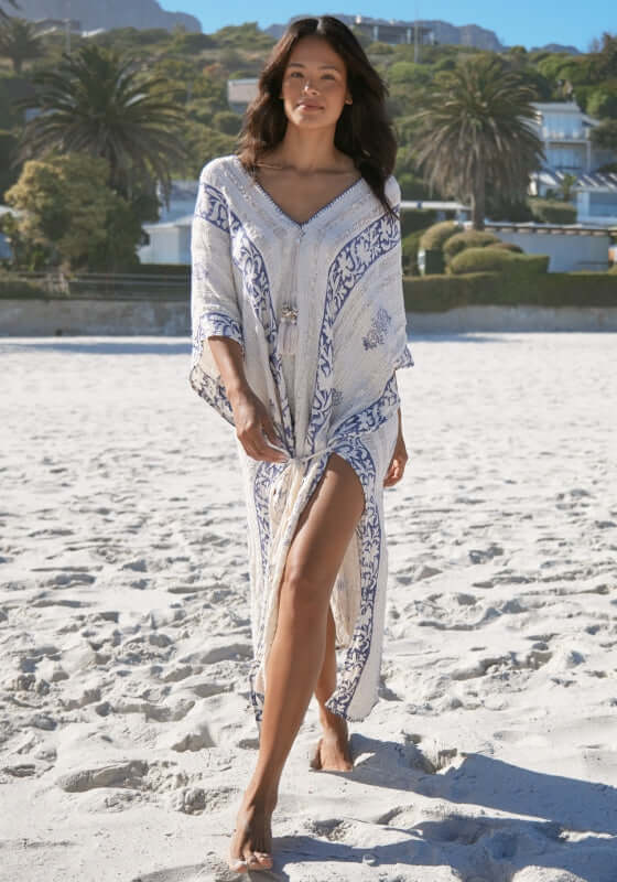 Gaya Kaftan by Miss June, model in off-white slouchy kaftan with navy print, featuring leg slits, walking on the beach.