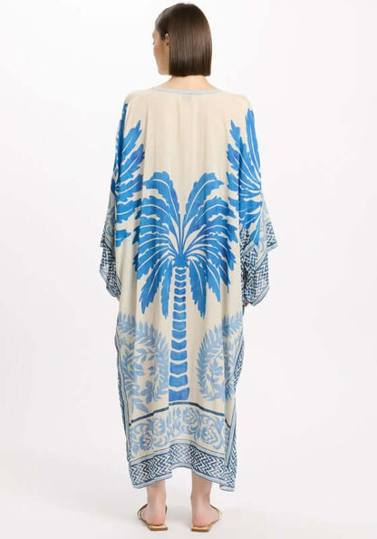 Rhoda Long Kaftan Blue by Miss June, showcasing a palm print in Mediterranean blue on a natural beige background.