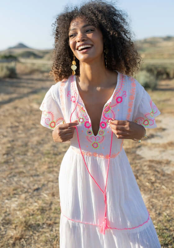 Holbox Long Dress Natural by Piti Cuiti, featuring hand-embroidered details and a model smiling in a natural setting.