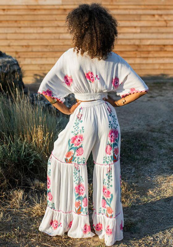 Bonaire Top White Pink by Piti Cuiti, showcasing a floral print with pink scallops seen from the back in a natural setting.
