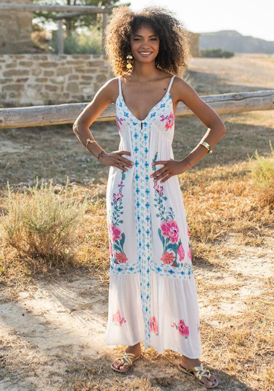 Bonaire Dress White Pink by Piti Cuiti on a model in a floral maxi dress in a sunlit outdoor setting.