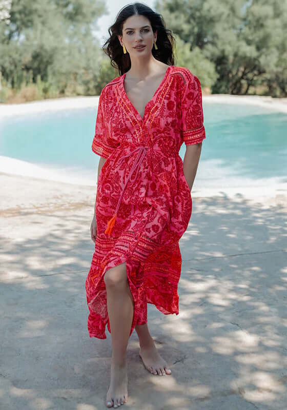 Samoa Short Sleeve Dress by Piti Cuiti showcasing vibrant red and pink paisley fabric by the poolside.