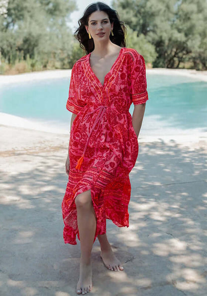 Samoa Short Sleeve Dress by Piti Cuiti showcasing vibrant red and pink paisley fabric by the poolside.