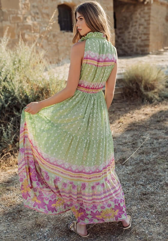 Curacao Dress Green by Piti Cuiti, showing the back of a woman in a green maxi dress with floral patterns.