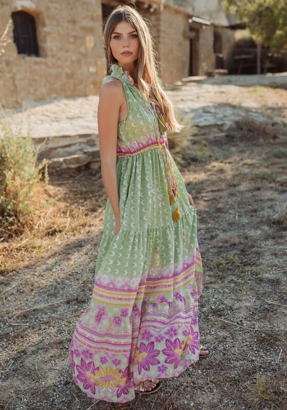Curacao Dress Green by Piti Cuiti, a flowy maxi dress with ruffled collar and tiered skirt in vibrant pink and green patterns.