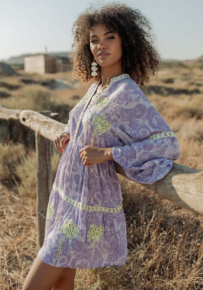 Sahara Purple Dress by Piti Cuiti, featuring vibrant lime green embroidery against a purple base in a natural setting.