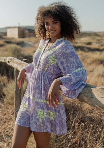 Sahara Purple Dress by Piti Cuiti, showcasing a model in a vibrant purple dress with lime green embroidery in a natural setting.