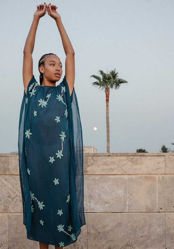 Cordelia Beaded Kaftan Navy by Pitusa features delicate beadwork and flowing silhouette against a scenic background.