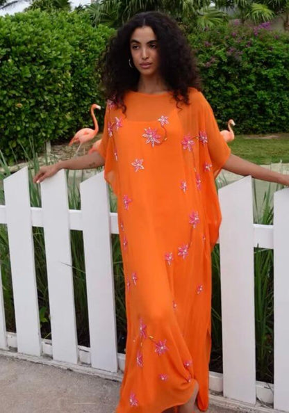 Cordelia Beaded Kaftan Orange by Pitusa, featuring delicate beadwork and a flowing silhouette in a stunning outdoor setting.