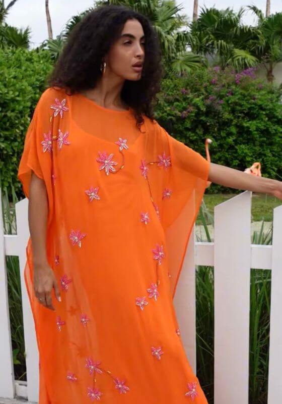 Cordelia Beaded Kaftan Orange by Pitusa, showcasing delicate beadwork and a flowing silhouette in an outdoor setting.