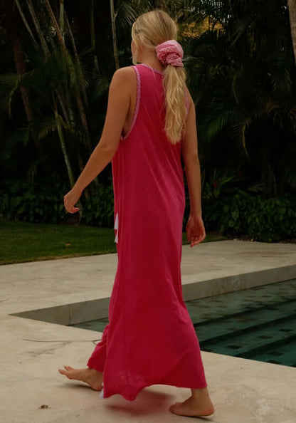 Monochrome Slit Dress Fuchsia by Pitusa, model walking by a pool in a fuchsia maxi dress with lilac tassel details.