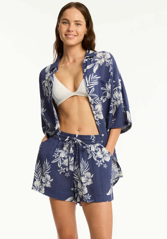 Aloha Beach Shirt French Navy by Sea Level worn by a model with bikini and shorts, showcasing floral print.