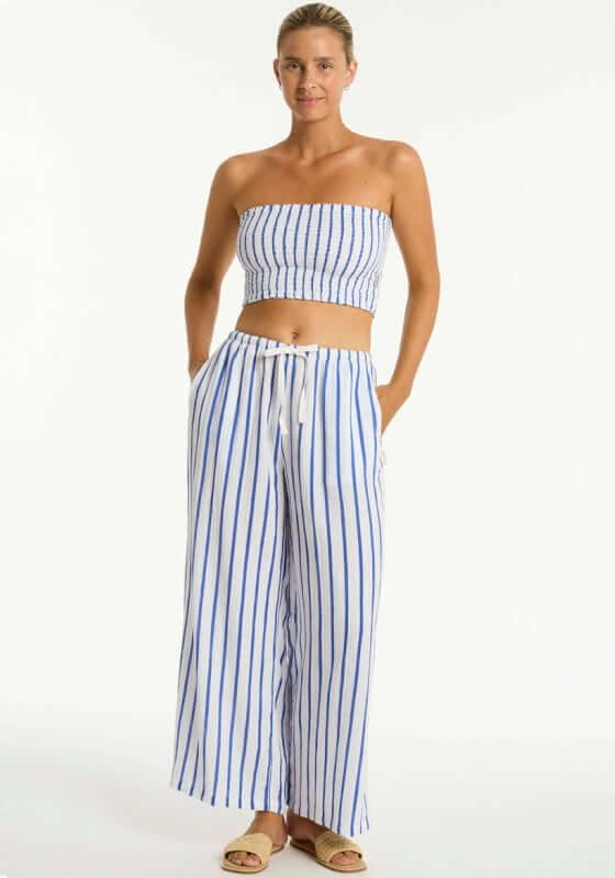 Amalfi Beach Trousers Blue by Sea Level, model wearing loose fit blue and white striped beach trousers with elastic waist.