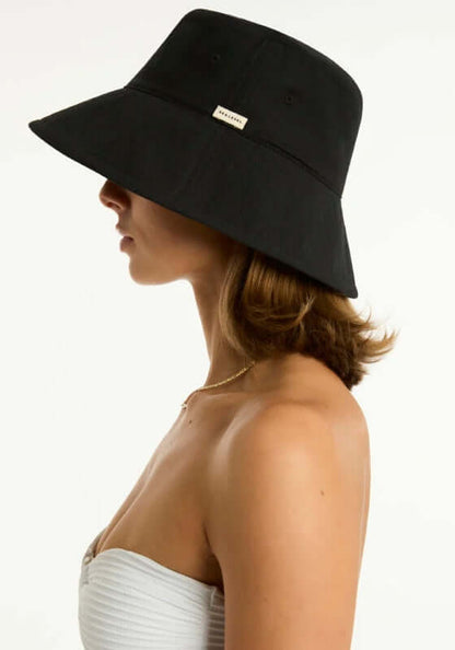 Canvas Bucket Beach Hat Black by Sea Level, stylish black foldable sunhat worn by a woman from the side.