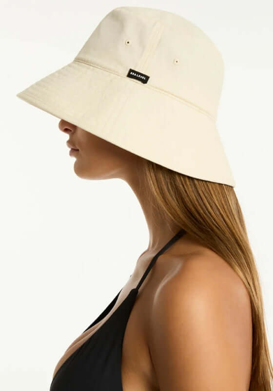 Canvas Bucket Beach Hat Ivory by Sea Level, woman wearing stylish ivory bucket hat on the beach side.