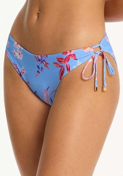 Indochine Twist Bandeau Bikini Light Blue by Sea Level side view of bikini bottoms with floral design and tie details.