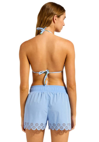 Boardshort Powder Blue by Seafolly, showing a model from the back in soft powder blue shorts with daisy embroidery.