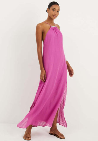 Lily Long Dress French Rose by Vix, a model wearing a pink maxi dress with open back and slits, showcasing beach elegance.